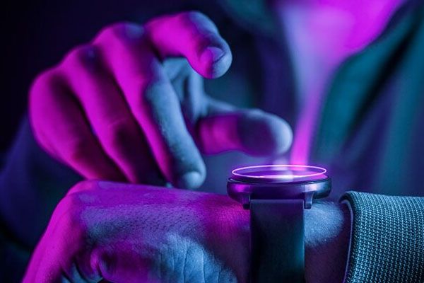 Primo piano delle mani che indossano uno smartwatch con un effetto ologramma futuristico