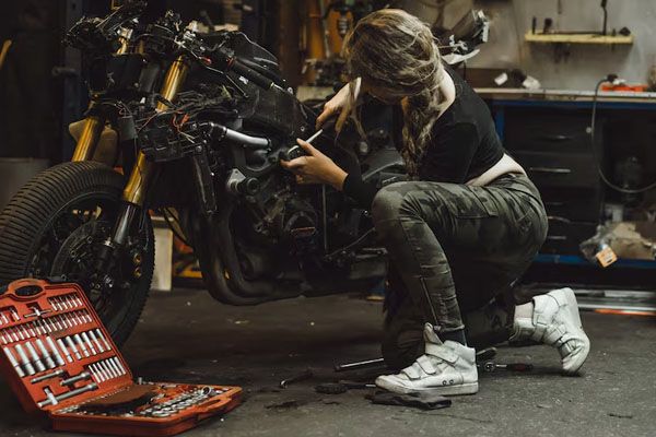 bella ragazza con i capelli lunghi in un garage che ripara una motocicletta