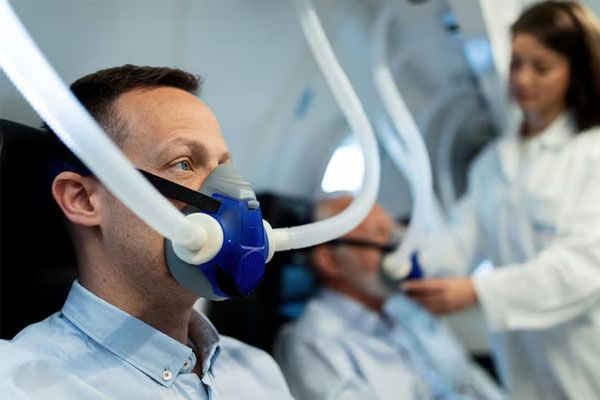 Uomo adulto che respira attraverso una maschera in una clinica di ossigenoterapia iperbarica