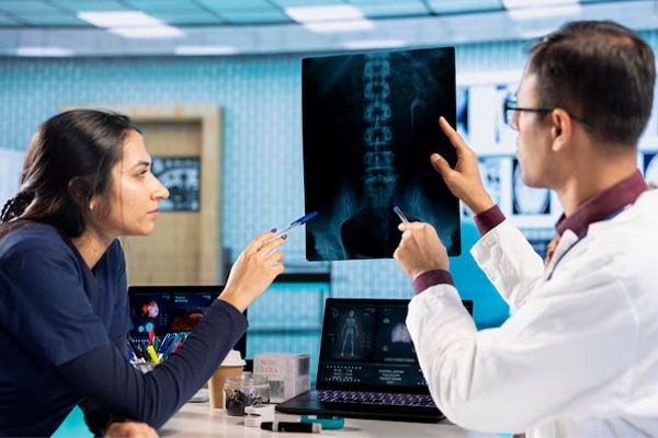 coppia di operatori sanitari che controllano e puntano la radiografia del paziente