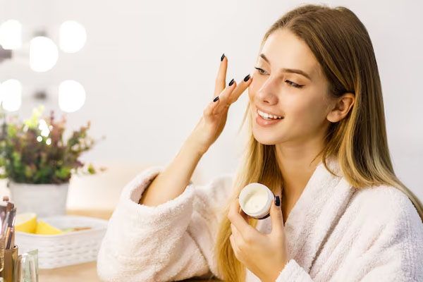 donna a casa che applica la crema mascara