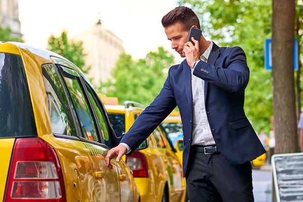 giovane che cammina verso un taxi e parla al telefono