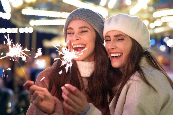 Migliori amici che tengono in mano delle stelle filanti al mercatino di Natale