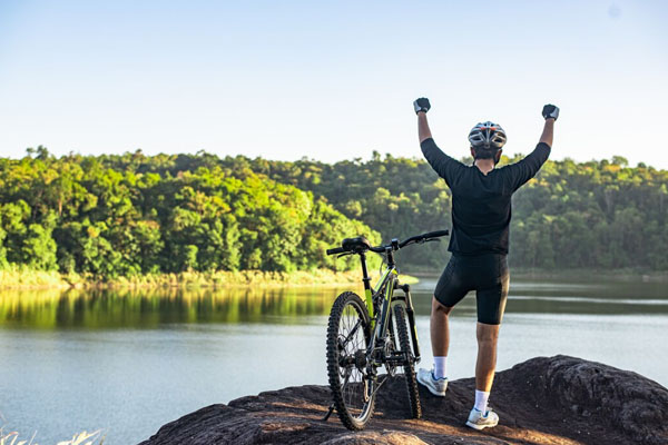 Ciclista in escursione che festeggia di fronte a un paesaggio panoramico