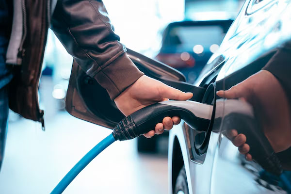 Primo piano di una mano che inserisce un caricabatterie su un'auto elettrica