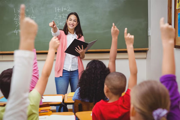 Un'insegnante in classe con i suoi studenti che alzano la mano